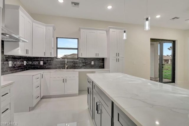 3114 39th St SW, Lehigh Acres, FL 33976 - kitchen with light stone counters, a sink, hanging light fixtures, visible vents, and decorative backsplash
