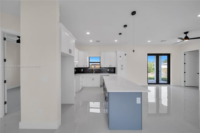3114 39th St SW, Lehigh Acres, FL 33976 - kitchen with white cabinetry, decorative backsplash, a kitchen island, a sink, and a ceiling fan