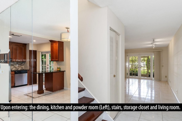 kitchen with backsplash, dishwasher, light tile patterned floors, baseboards, and dark countertops