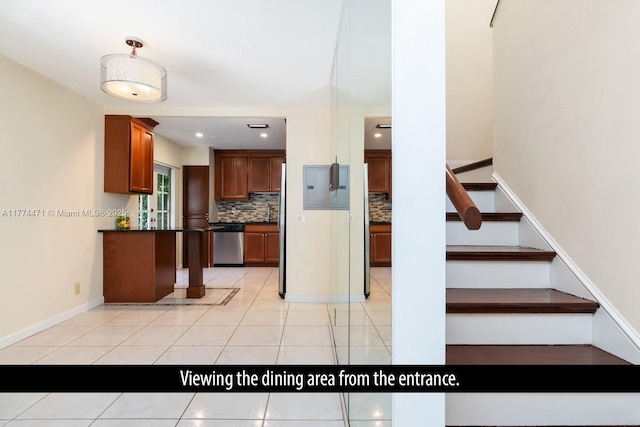 kitchen featuring dishwasher, brown cabinets, light tile patterned floors, dark countertops, and decorative backsplash