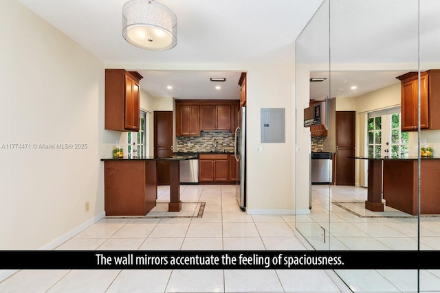 kitchen with decorative backsplash, electric panel, dark countertops, appliances with stainless steel finishes, and light tile patterned floors