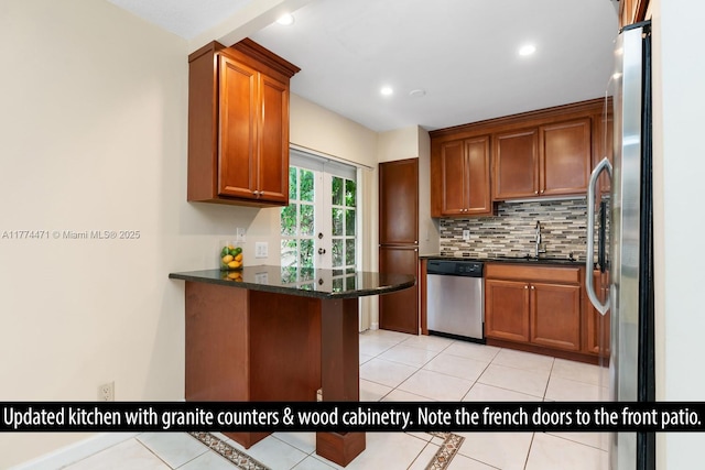 kitchen featuring tasteful backsplash, stainless steel appliances, a sink, light tile patterned flooring, and a peninsula