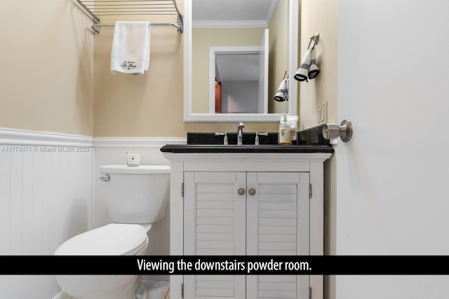 bathroom featuring a wainscoted wall, ornamental molding, toilet, and vanity