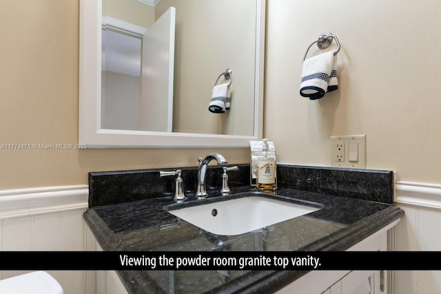 bathroom featuring wainscoting, vanity, and a decorative wall