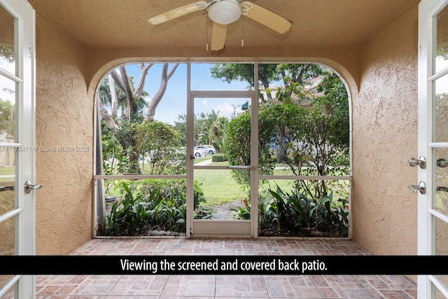 unfurnished sunroom with french doors, a ceiling fan, and a textured wall