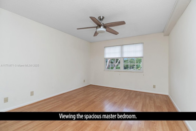 empty room featuring a textured ceiling, wood finished floors, baseboards, and a ceiling fan