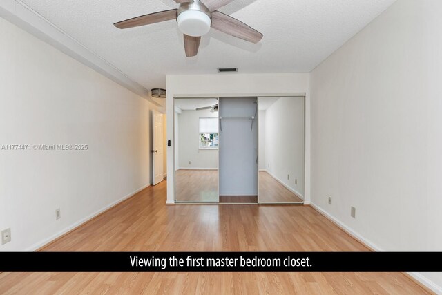 unfurnished bedroom featuring a closet, wood finished floors, a textured ceiling, baseboards, and visible vents