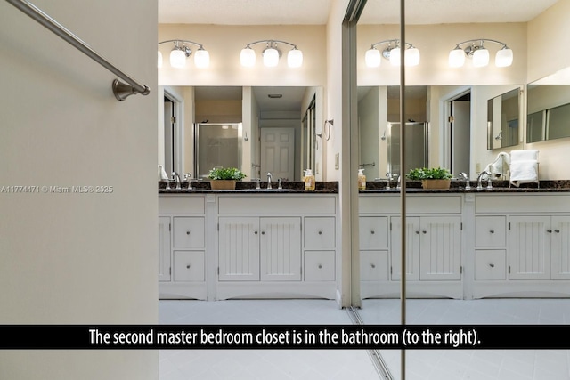 full bath with tile patterned flooring, a shower stall, and two vanities