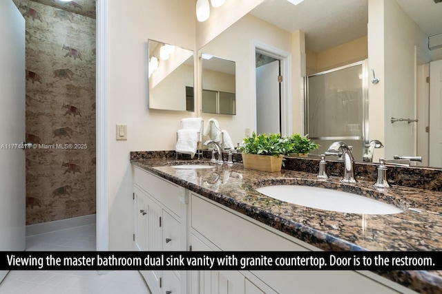 bathroom featuring double vanity, a sink, a stall shower, and tile patterned flooring