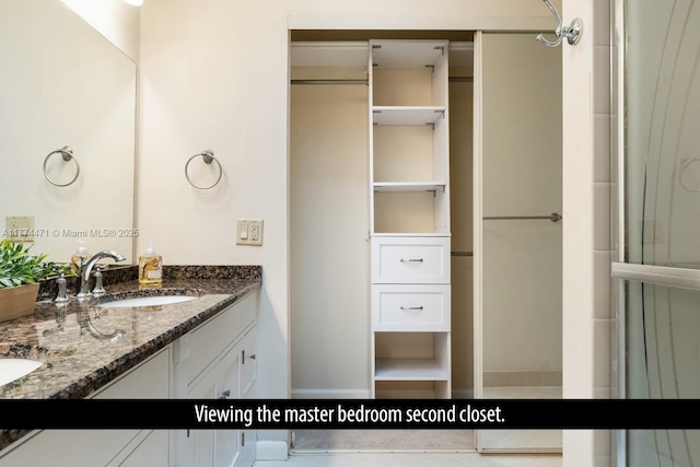 bathroom with double vanity, a sink, and a shower
