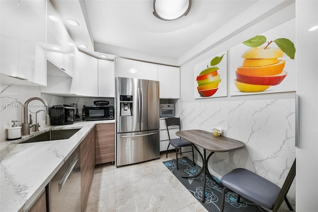 kitchen featuring modern cabinets, a sink, white cabinetry, and appliances with stainless steel finishes