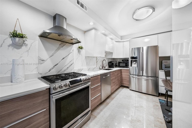 kitchen with visible vents, wall chimney exhaust hood, modern cabinets, appliances with stainless steel finishes, and white cabinetry