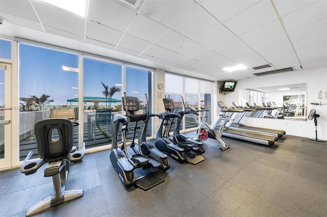 workout area with visible vents, a drop ceiling, and a wall of windows