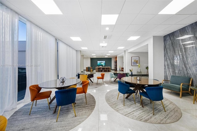dining space featuring marble finish floor, a drop ceiling, and visible vents