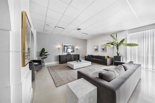 living room featuring baseboards, a drop ceiling, and visible vents