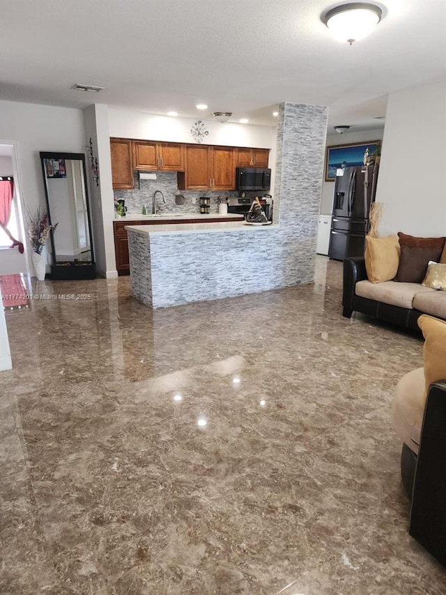 kitchen featuring visible vents, open floor plan, light countertops, appliances with stainless steel finishes, and brown cabinets