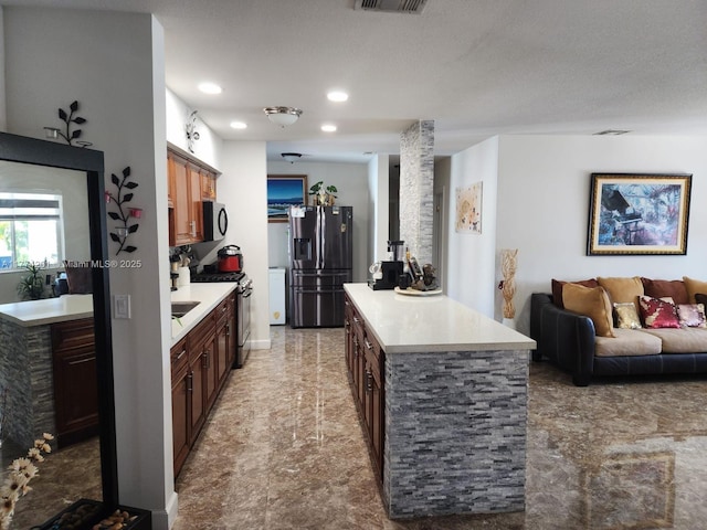 kitchen with open floor plan, light countertops, appliances with stainless steel finishes, recessed lighting, and a kitchen island