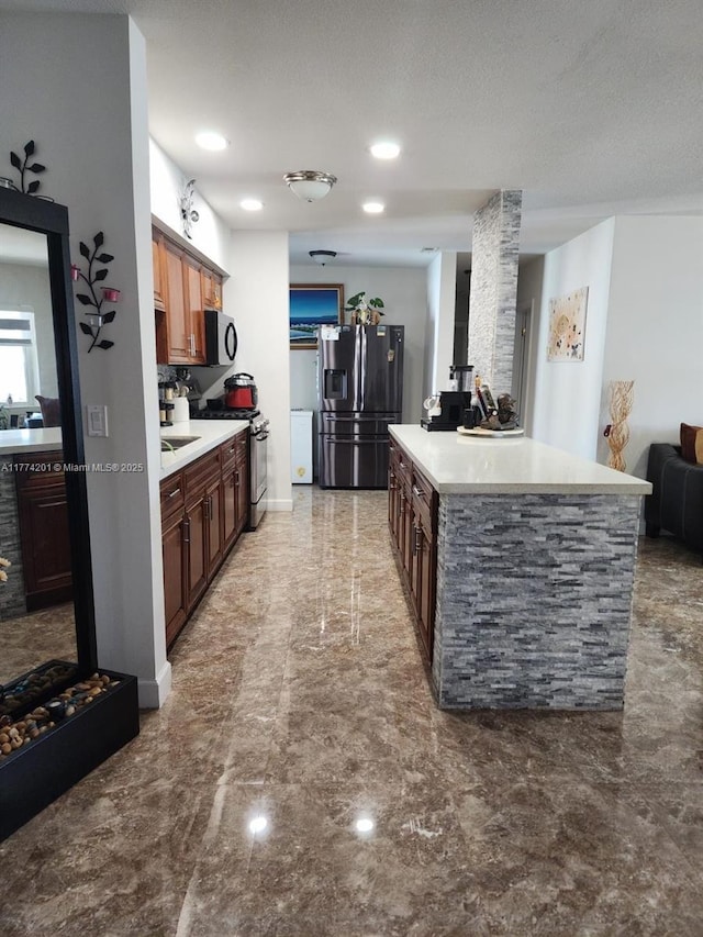 kitchen featuring a textured ceiling, a kitchen island, marble finish floor, light countertops, and stainless steel appliances