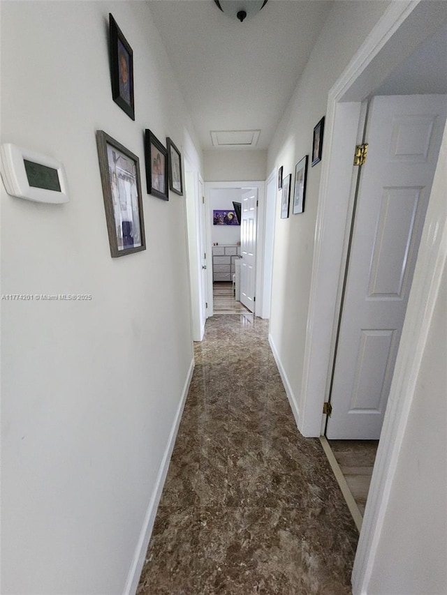 corridor with baseboards and attic access