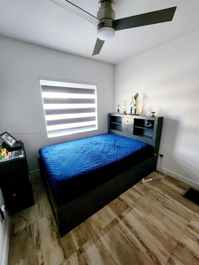 bedroom with ceiling fan, wood finished floors, and baseboards