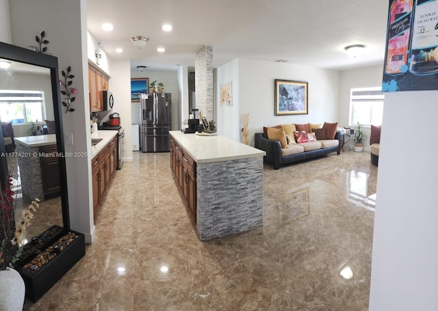 kitchen featuring brown cabinetry, light countertops, marble finish floor, and stainless steel appliances