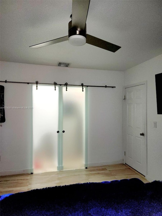 interior space with light wood-style floors, ceiling fan, visible vents, and a textured ceiling