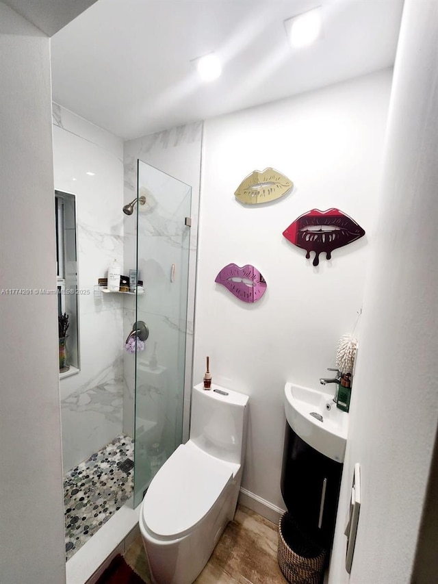 full bath featuring toilet, baseboards, a sink, and a marble finish shower