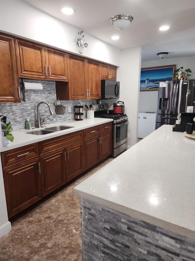 kitchen featuring brown cabinetry, light countertops, a sink, stainless steel appliances, and backsplash