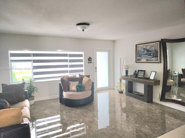 living room featuring marble finish floor, baseboards, and a textured ceiling
