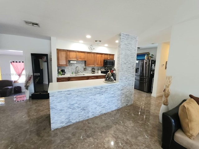 kitchen featuring a sink, open floor plan, light countertops, brown cabinetry, and stainless steel appliances