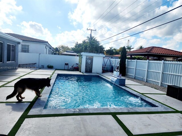 view of swimming pool featuring a fenced in pool, a patio area, a fenced backyard, and an outbuilding