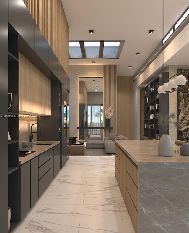 kitchen with light countertops, a sink, modern cabinets, open floor plan, and marble finish floor