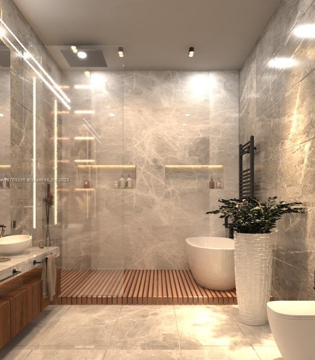 bathroom with a soaking tub, vanity, a shower with door, and tile walls