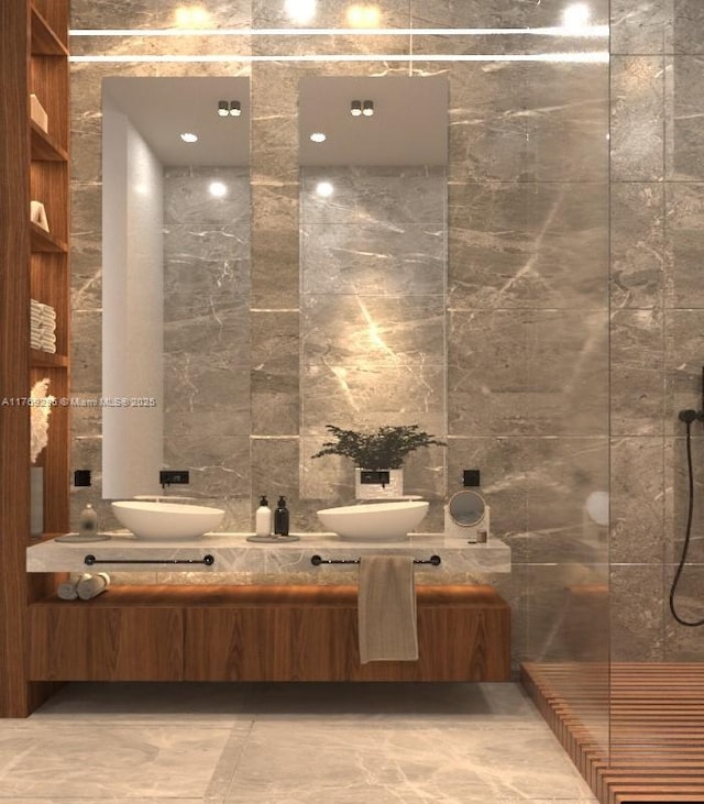 full bathroom with tile walls, double vanity, a walk in shower, and a sink