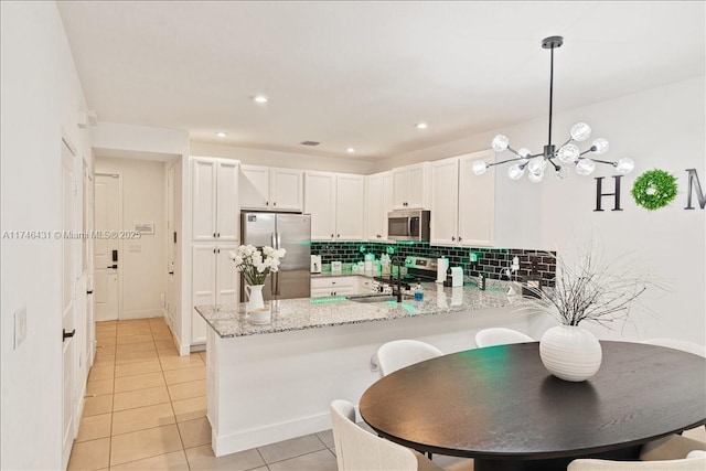 23300 SW 110th Ct, Homestead, FL 33032 - kitchen featuring a peninsula, stainless steel appliances, light stone counters, backsplash, and light tile patterned floors