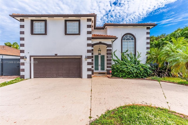 mediterranean / spanish home featuring stucco siding, french doors, a tiled roof, decorative driveway, and a garage