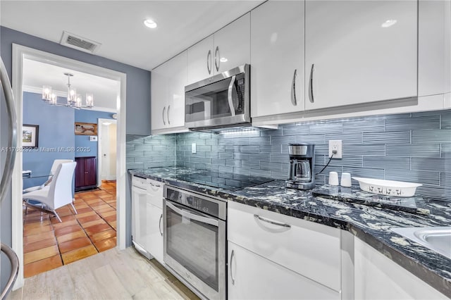 kitchen featuring visible vents, an inviting chandelier, backsplash, white cabinetry, and appliances with stainless steel finishes