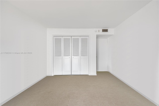 unfurnished bedroom with baseboards, carpet floors, visible vents, and a closet