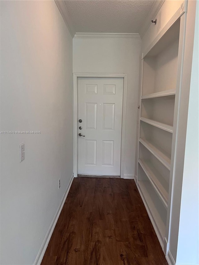 doorway featuring dark wood-type flooring, ornamental molding, a textured ceiling, and baseboards