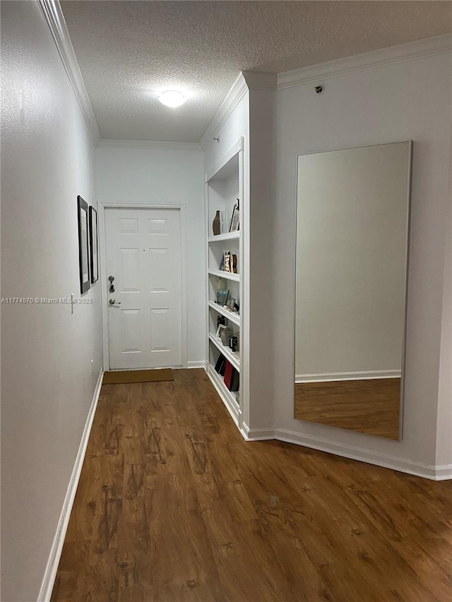 hall featuring crown molding, a textured ceiling, built in features, and wood finished floors