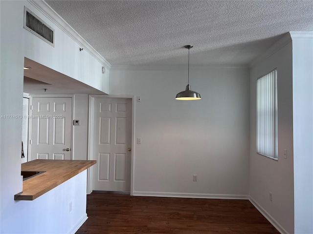 kitchen featuring crown molding, a textured ceiling, butcher block countertops, dark wood-type flooring, and visible vents