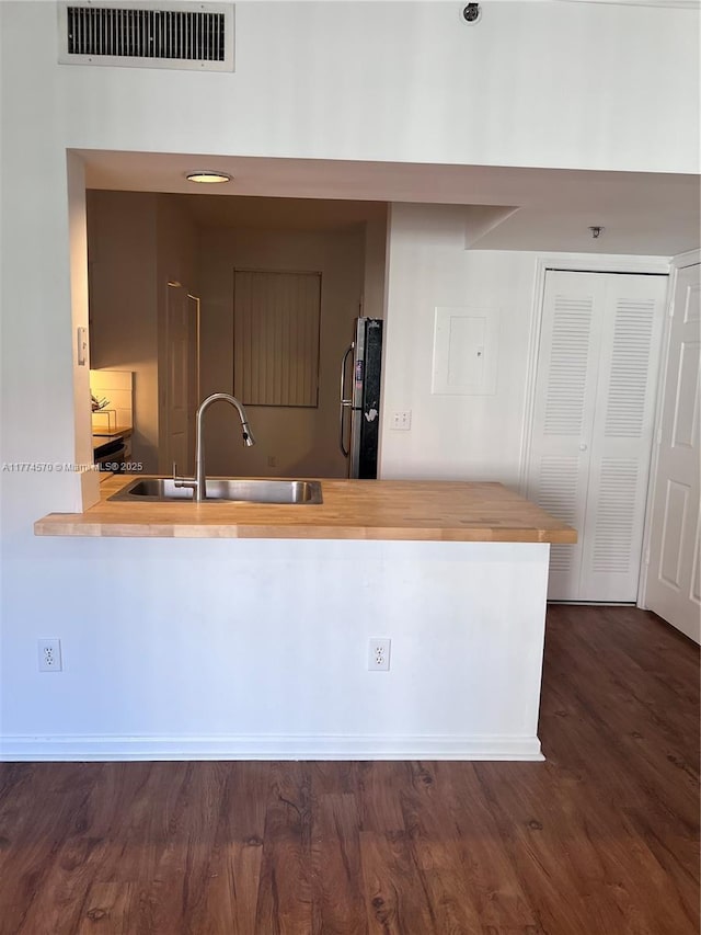 kitchen featuring visible vents, freestanding refrigerator, dark wood-style flooring, wooden counters, and a sink