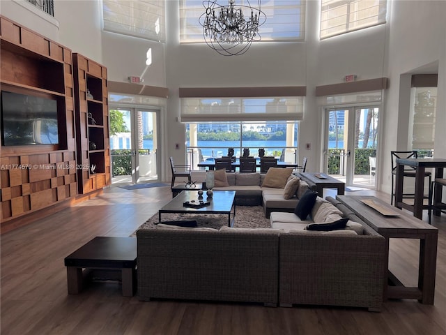 living room featuring wood finished floors, a high ceiling, a chandelier, and a wealth of natural light