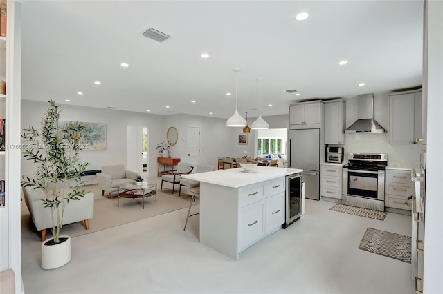 kitchen featuring appliances with stainless steel finishes, beverage cooler, visible vents, open floor plan, and wall chimney exhaust hood