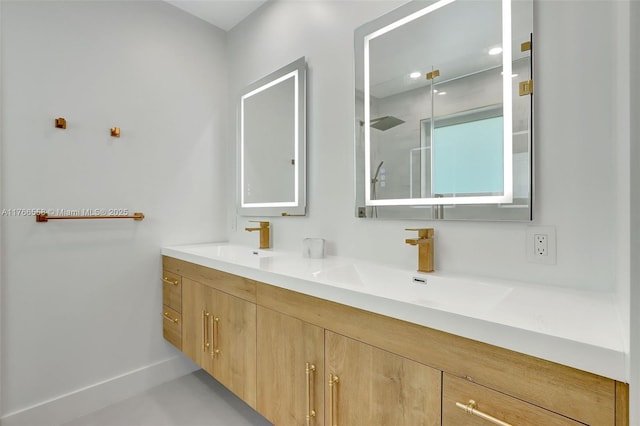 bathroom with baseboards, a walk in shower, double vanity, and a sink
