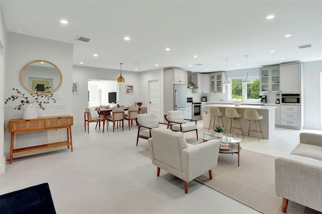 living area with recessed lighting, visible vents, and finished concrete floors