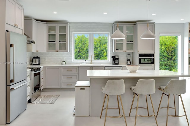 kitchen featuring light countertops, a kitchen island, appliances with stainless steel finishes, and tasteful backsplash