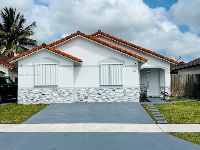 17707 SW 144th Ave, Miami, FL 33177 - mediterranean / spanish house featuring stone siding, a tile roof, stucco siding, and fence