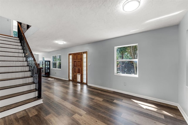 entryway featuring dark wood-type flooring, baseboards, stairs, and a textured ceiling