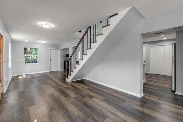 interior space featuring stairs, dark wood-style flooring, baseboards, a textured ceiling, and visible vents